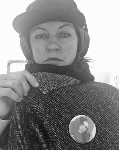 Black and white photo of Alyssa Berg who pulls at her jacket and wears a warm looking hat.